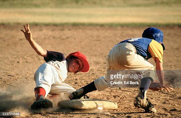 young baseball player sliding into base - ungdomsliga för baseboll och softboll bildbanksfoton och bilder