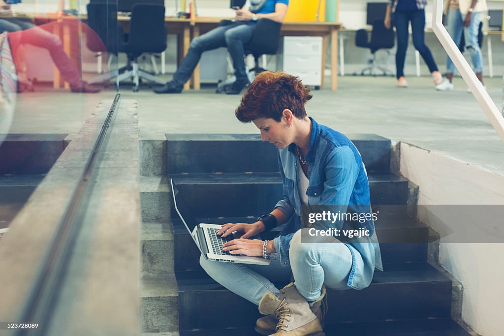 Woman Sitting on stairs and using her laptop.