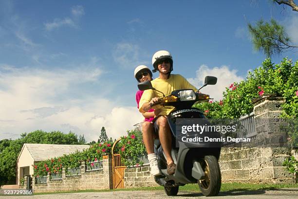 couple riding a motor scooter - bermudas islas del atlántico fotografías e imágenes de stock