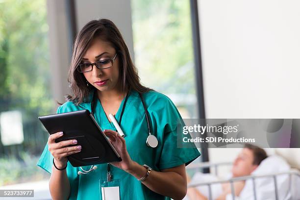 nurse using digital patient chart while taking care of patient - nurses looking at chart stock pictures, royalty-free photos & images
