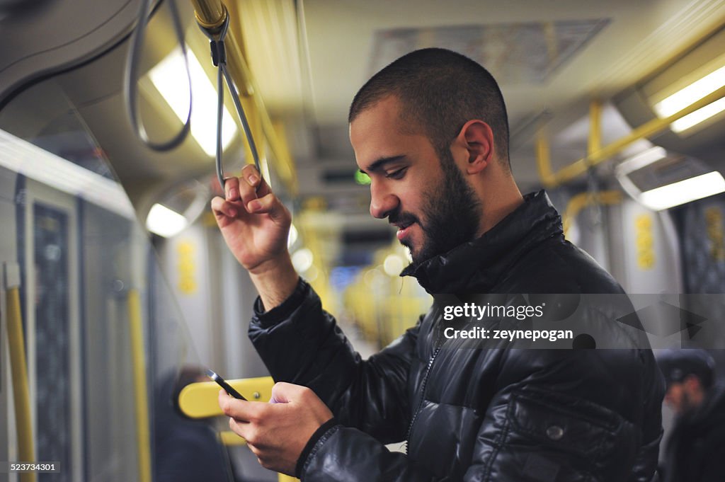 Giovane uomo, guardando il suo smartphone in treno