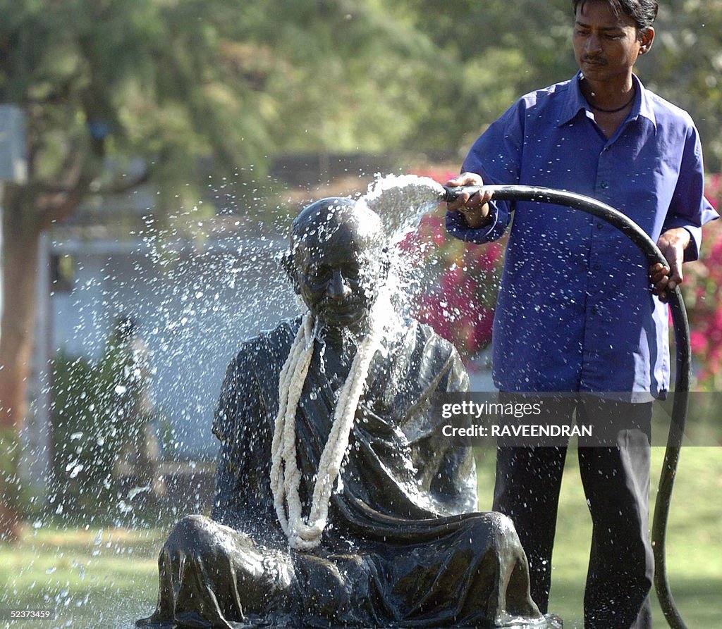 A worker cleans a statue of Mahatma Gand
