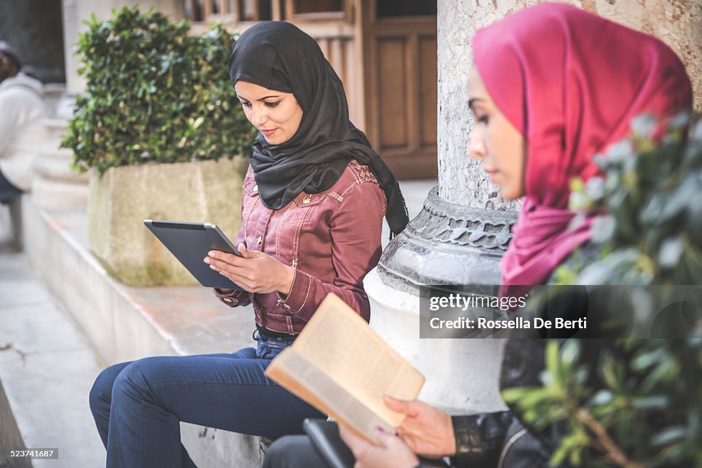Students Reading On Paper Book And Tablet