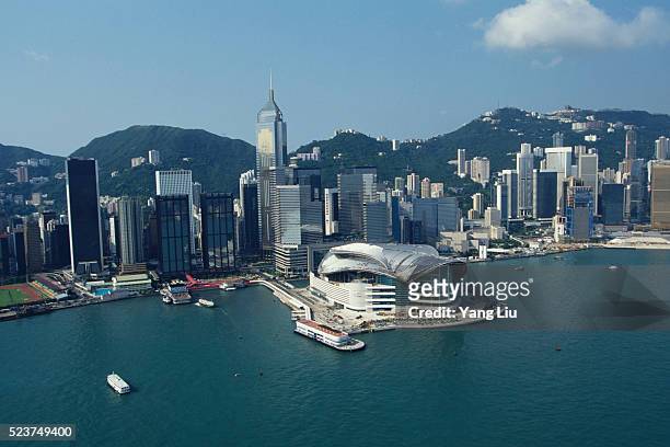 hong kong convention and exhibition center with skyscrapers behind - hong kong harbour stock pictures, royalty-free photos & images