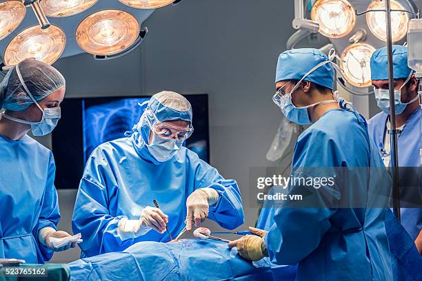 os médicos da equipe na sala de cirurgia com assistência - operação imagens e fotografias de stock