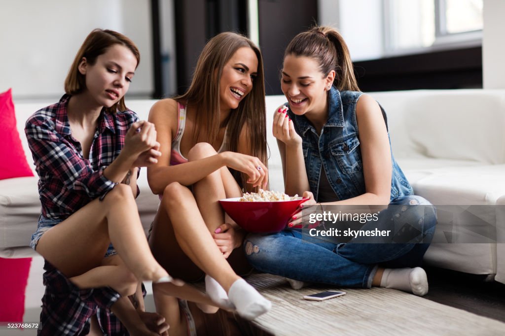 Mujer joven feliz comiendo palomitas de maíz en su hogar.