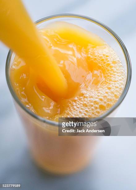 orange juice pour overhead - orange juice stock-fotos und bilder