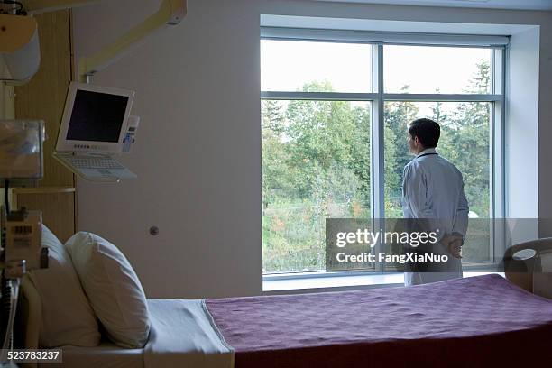 médecin en regardant un patient en pédiatrie fenêtre de la chambre - hands behind back stock photos et images de collection