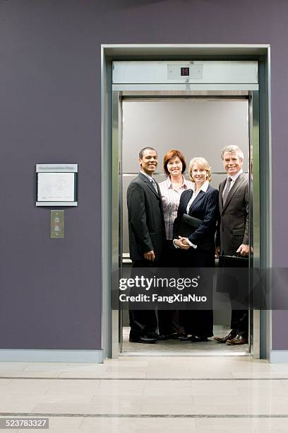 administrative workers smiling in elevator - open elevator stock pictures, royalty-free photos & images