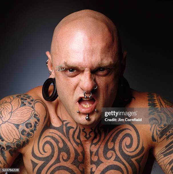 fierce man with body piercings and tattoos - body piercings stock-fotos und bilder