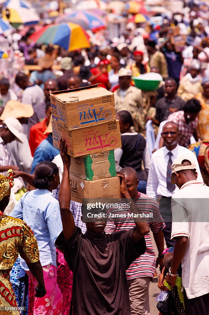 Worker Carrying Boxes in Nigerian Market
