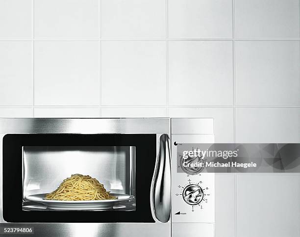 pasta inside a microwave oven - microwave oven stock pictures, royalty-free photos & images