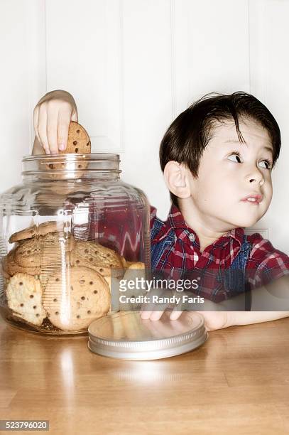 boy with hand caught in the cookie jar - pot met koekjes stockfoto's en -beelden