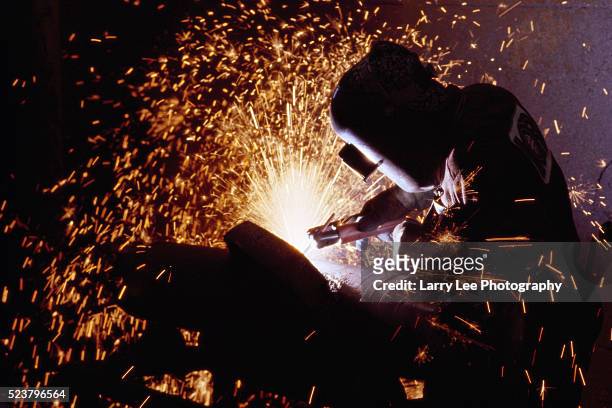 man welding in factory - soldar fotografías e imágenes de stock