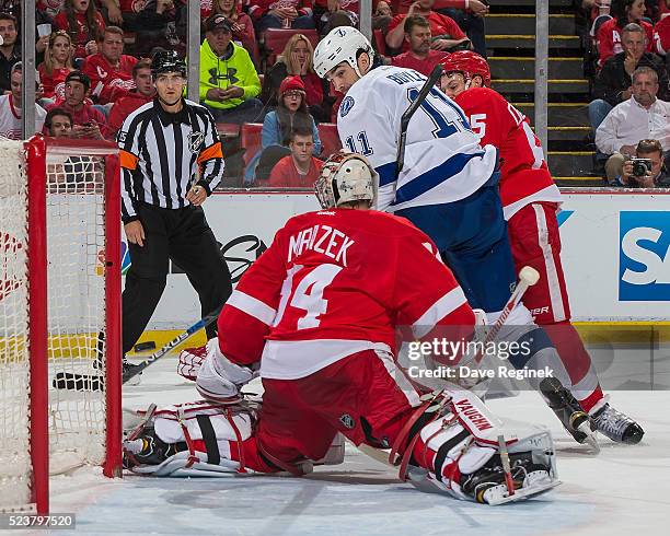 Brian Boyle of the Tampa Bay Lightning backhands at the puck through the goal mouth behind Petr Mrazek of the Detroit Red Wings in Game Four of the...
