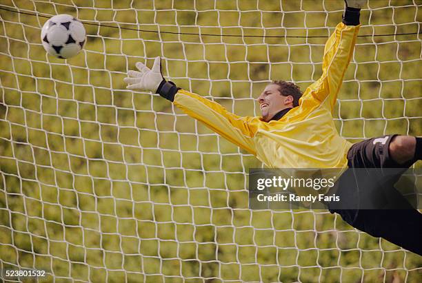 goalkeeper diving for the ball - tor schießen stock-fotos und bilder