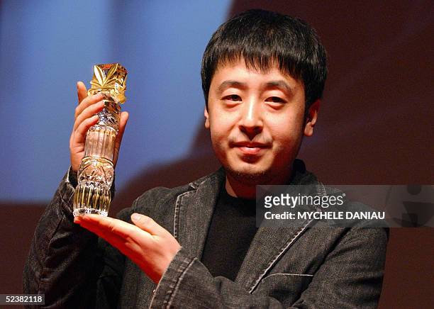 Chinese director Jia Zhang-Ke holds his trophy 13 March 2005 after winning the Lotus of the best screenplay with his film "The World" , during the...