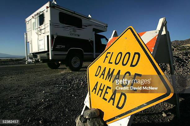 Camper travels past a yellow road warning sign, advising motorists of flood damaged roads in the Death Valley region due to recent heavy rains and...