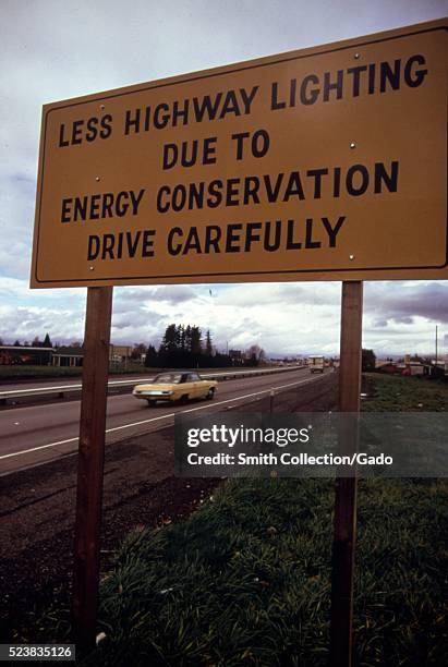 Posted highway sign along interstate 5 explains lack of highway lighting is due to energy conservation. Image courtesy National Archives, United...