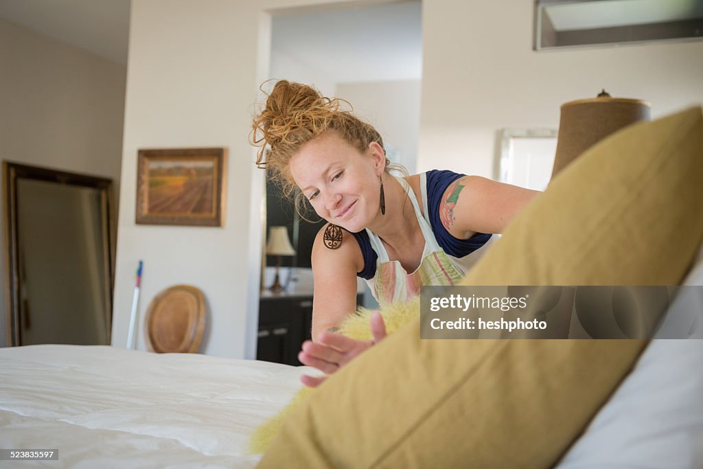 Young woman cleaning bedroom with green cleaning products