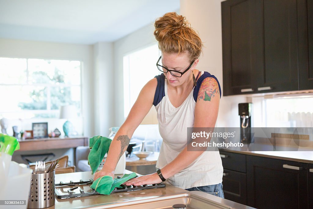 Young woman cleaning kitchen with green cleaning products