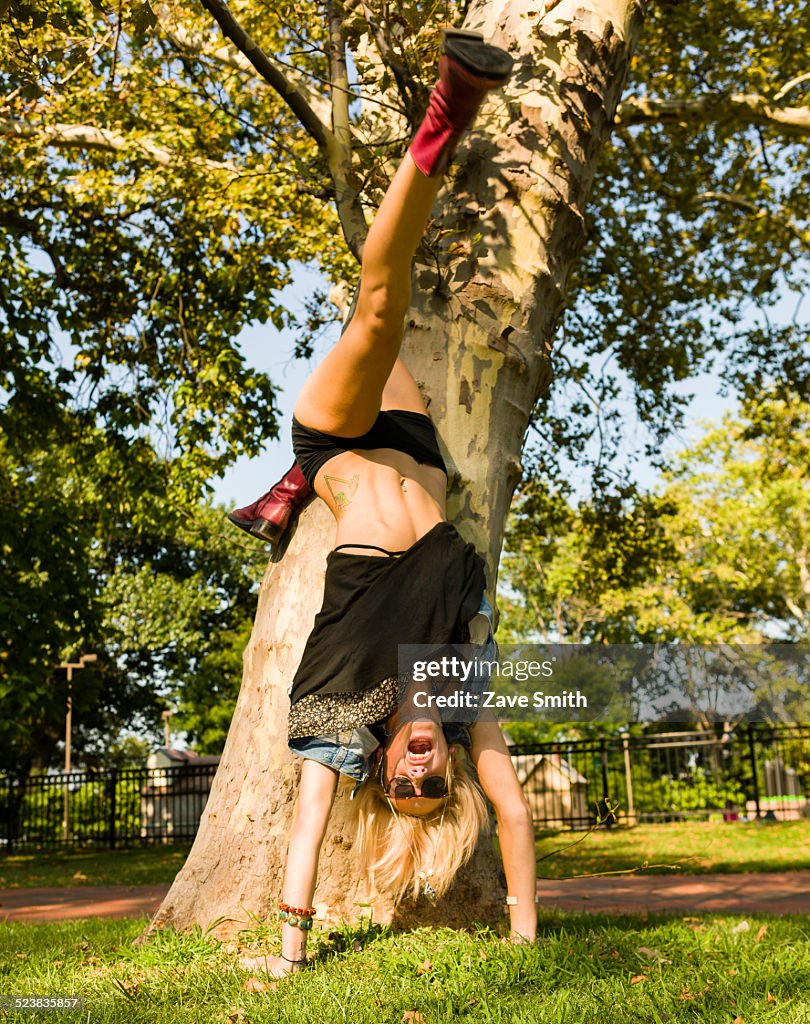 Young woman doing handstand in park