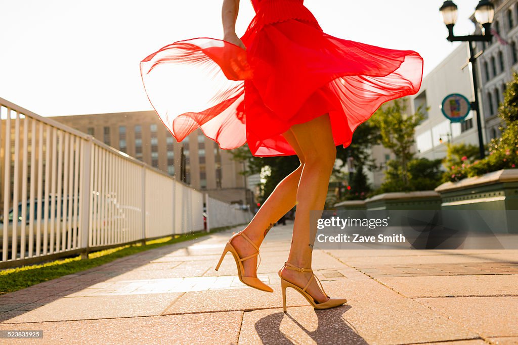 Waist down view of young woman twirling whilst wearing red dress