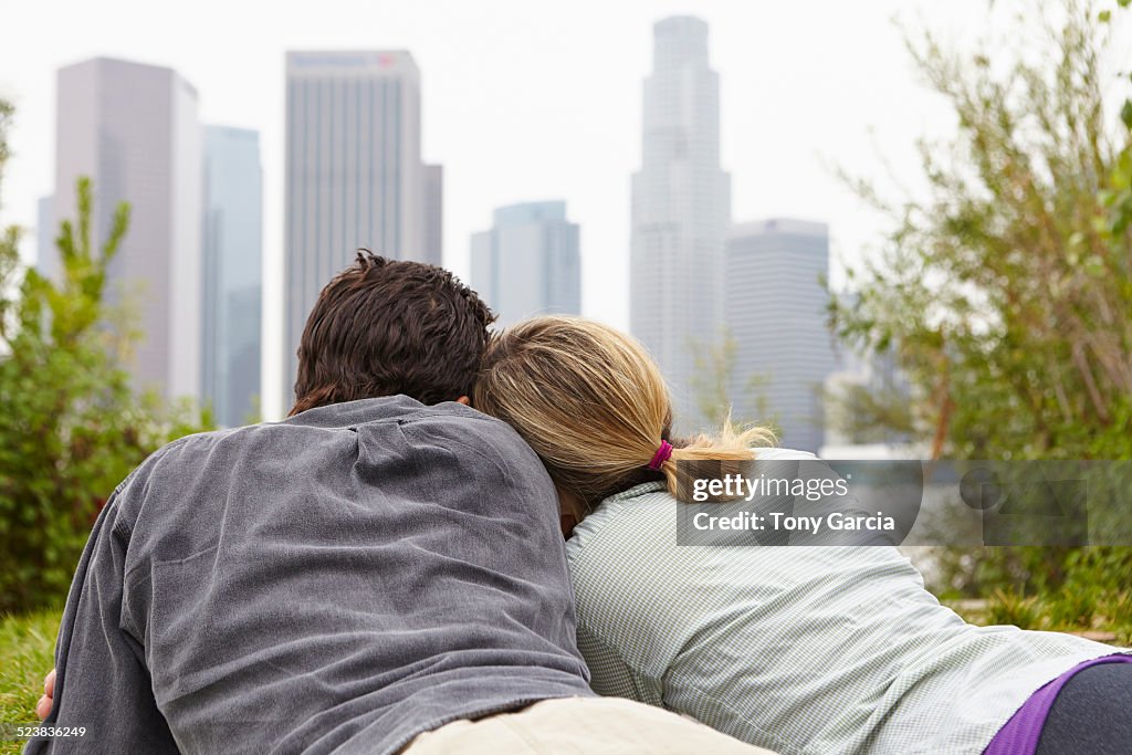 Couple relaxing in park by city