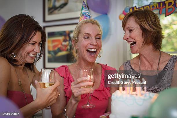 three mature women at birthday party, laughing - holding birthday cake stock pictures, royalty-free photos & images