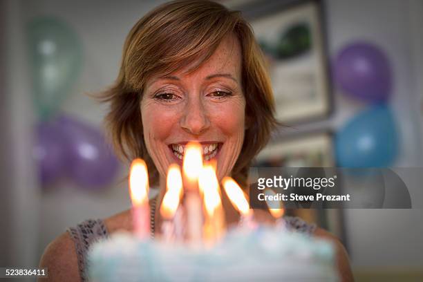 mature woman holding birthday cake with candles - woman holding cake stock-fotos und bilder