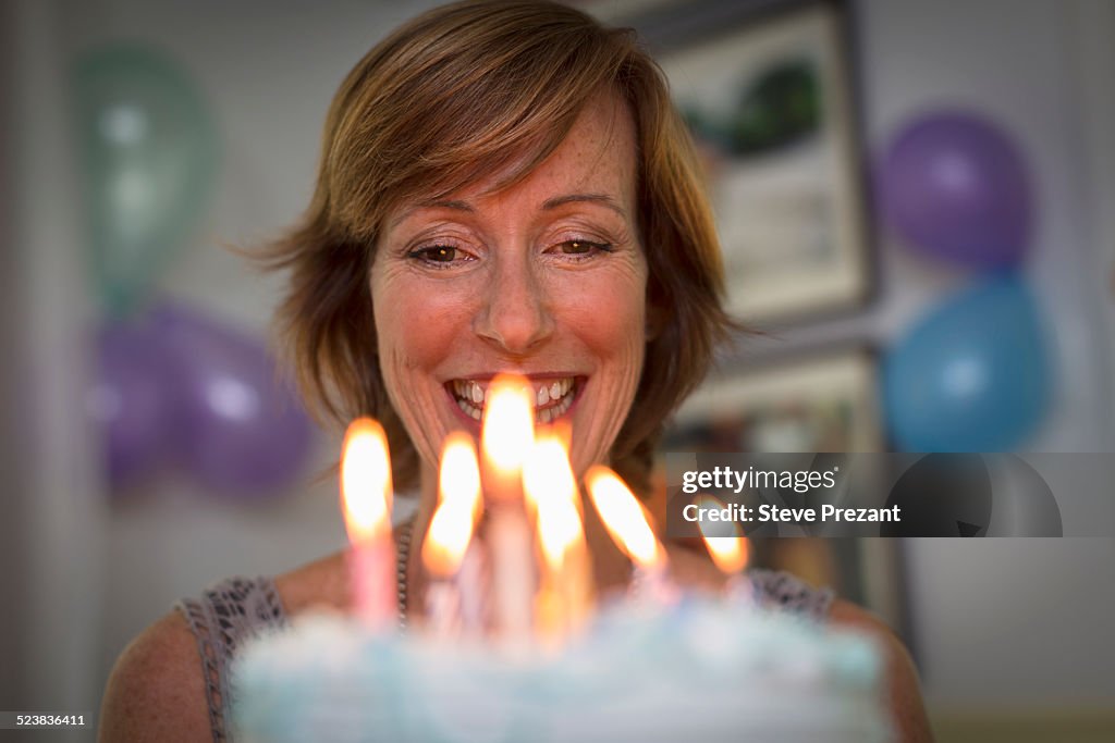 Mature woman holding birthday cake with candles