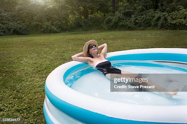 mature woman relaxing in paddling pool - childrens pool stock pictures, royalty-free photos & images