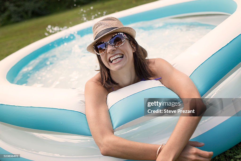 Mature woman in paddling pool, splashing water