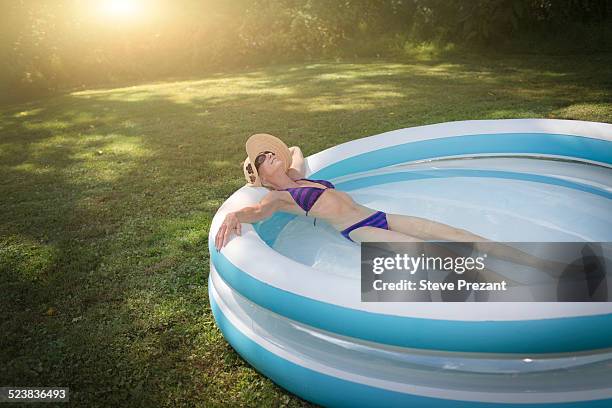 mature woman relaxing in paddling pool - older woman bathing suit stock pictures, royalty-free photos & images