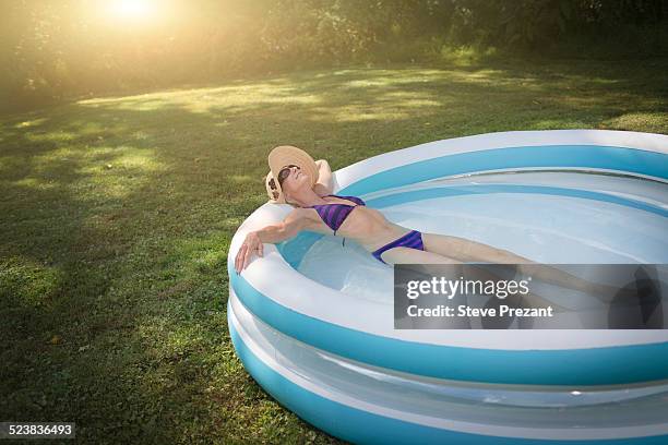 mature woman relaxing in paddling pool - badkläder bildbanksfoton och bilder