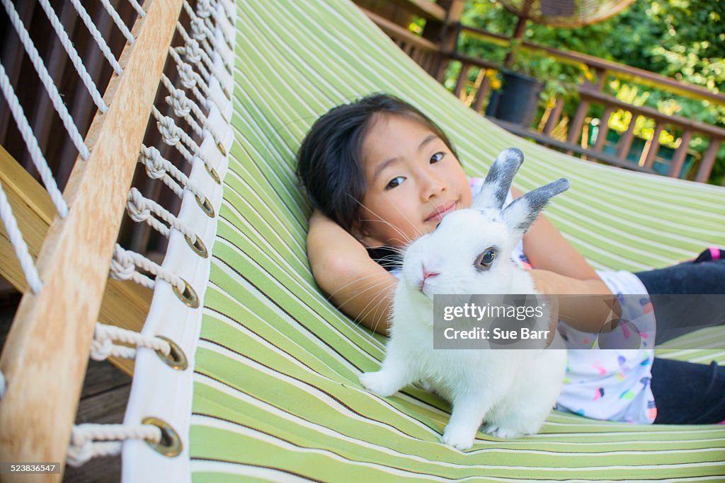 Young asian girl on hammock with pet rabbit