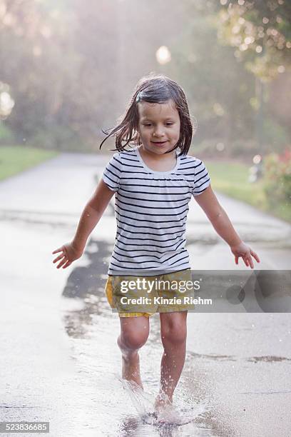 barefoot girl running through puddles on rainy street - wet girl stock-fotos und bilder