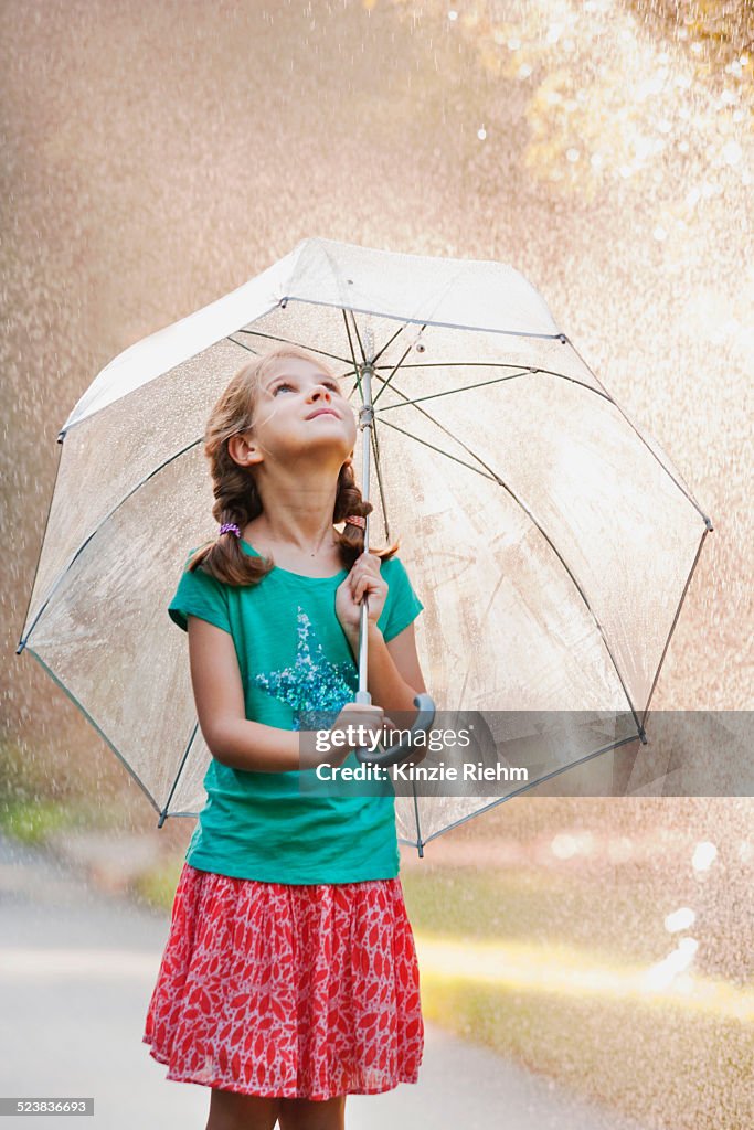 Girl holding up umbrella on rainy street