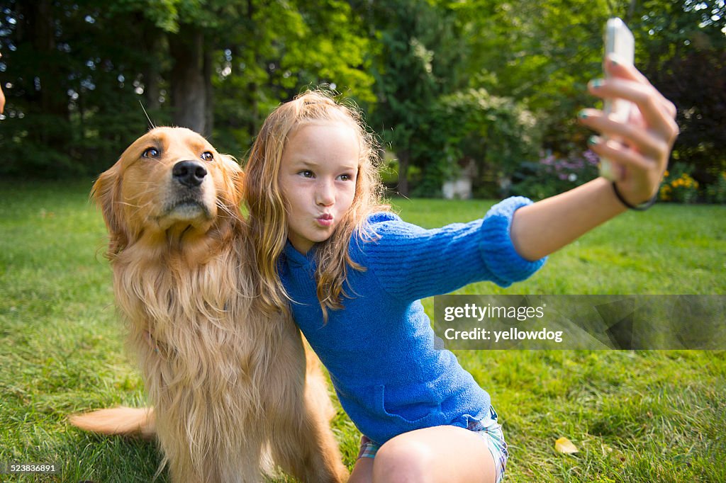 Girl taking selfie with pet dog in garden