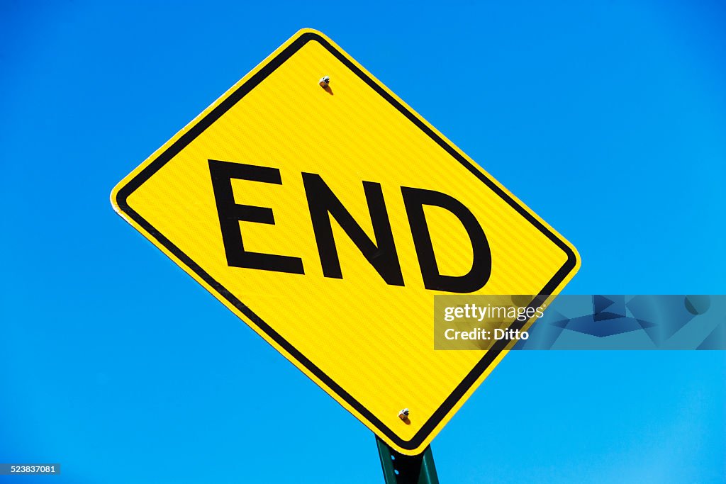 Yellow road sign against blue sky with word - end