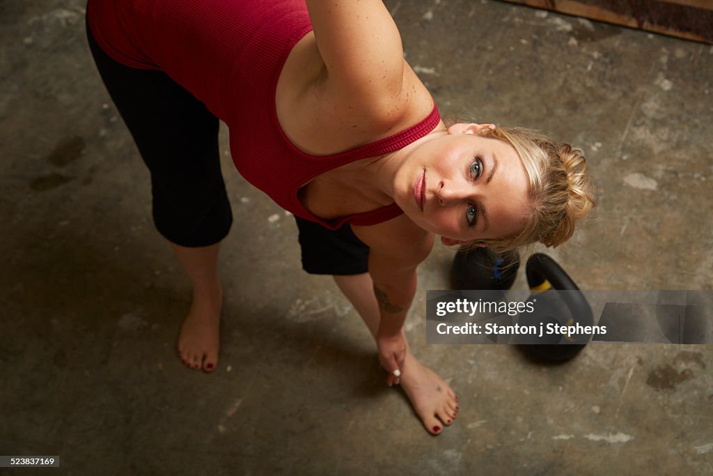 Mid adult female athlete lifting kettlebells in gym