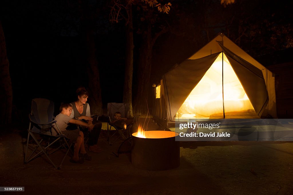 Mature woman and two sons watching campfire at night, County Park, Los Angeles, California, USA