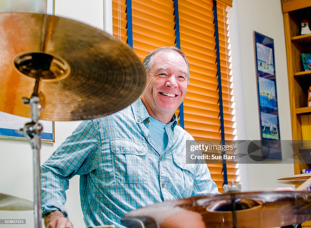 Mature man playing drums at home