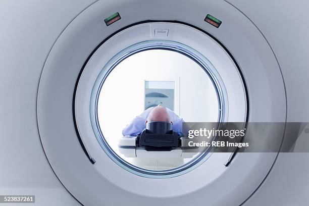 patient lying down on ct scanner - équipement médical photos et images de collection