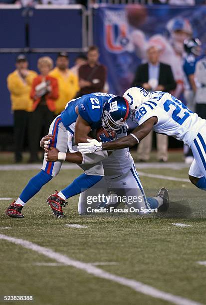 Tiki Barber of the New York Giants carries the ball and gets tackled by Montae Reagor and Marlin Jackson of the Indianapolis Colts during an NFL...