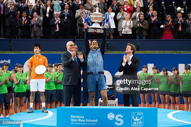 Rafael Nadal of Spain raises the trophy between President of Banc Sabadell Josep Oliu and Carlos Godo after defeating Kei Nishikori of Japan in the...