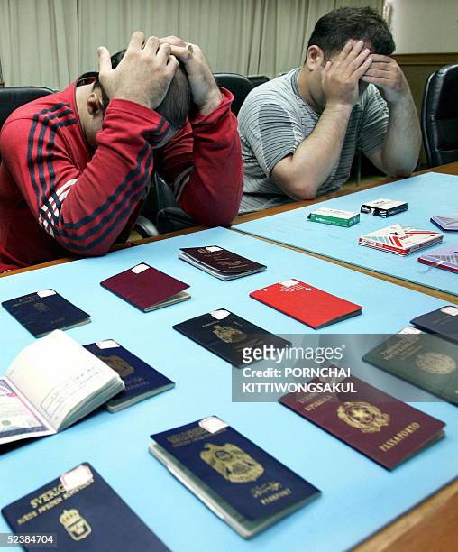 Iranian suspects Amir Zargar Ablolhamid and Nurbakhsh Pana Hidoshanlou cover their faces during a press conference at Thai Immigration Bureau in...