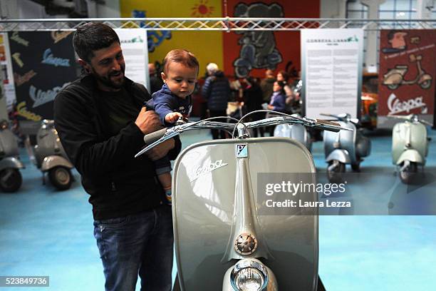 People attend the exhibition and look at the very first model of Vespa appeared in 1946 during the celebration of 70 years of the Vespa scooter in...