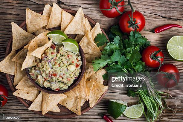 homemade guacamole sauce and corn chips in ceramic bowl on wooden table viewed from above, mexican food - raw food stock pictures, royalty-free photos & images