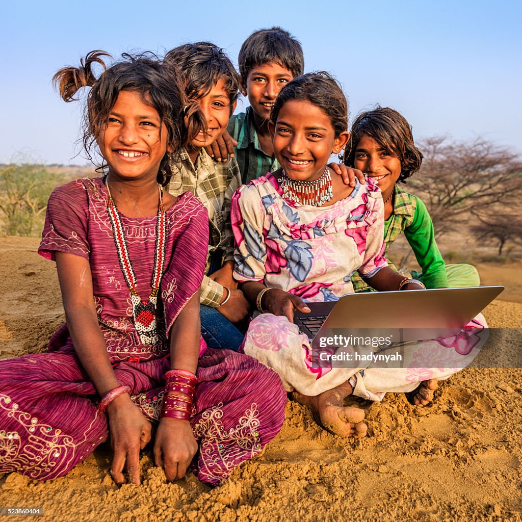 Happy Indian children using laptop, desert village, India